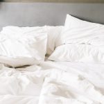 messy bed with white duvet and pillows
